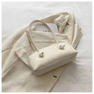 Détail d'un sac porté épaule blanc crème marbré avec nœuds décoratifs sur la bandoulière