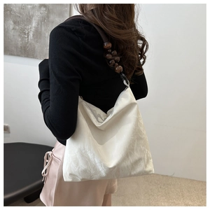 Detail of white textured velvet hobo bag with vintage brown wooden beaded strap on shoulder