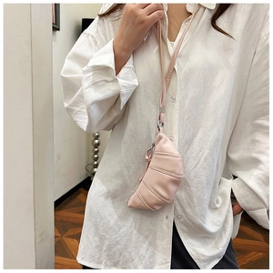 Detailed view of mini pink croissant crossbody bag with pleated texture and neck strap