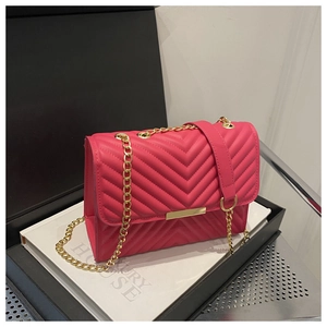 Detail of fuchsia quilted handbag with gold chain strap in a luxury gift box