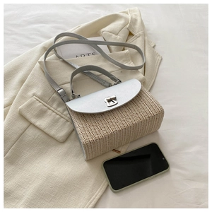 Straw crossbody bag with metal twist lock detail on beige suit and lifestyle props