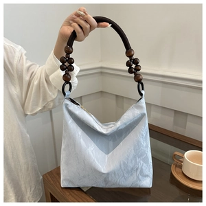 Detail of light blue velvet shoulder bag with chunky rope handle and wooden beads decoration