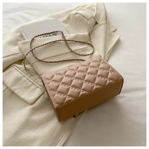 Detailed view of beige quilted handbag with chain strap on textured blazer fabric