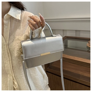 Detail of silver crossbody handbag with metallic finish and gold buckle on a model