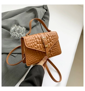 Detail of caramel crocodile embossed handbag featuring waffle texture and gold clasp
