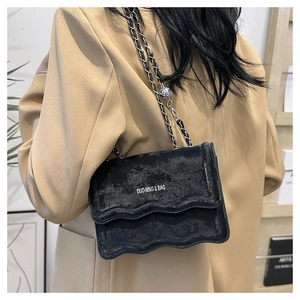 Detail of black chain bag featuring wavy edge design and adjustable silver metal ball