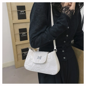 Close-up of white marble pattern shoulder bag with butterfly metal buckle on a model