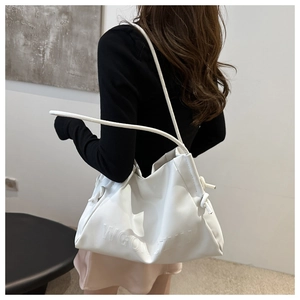 Dettaglio della borsa tote grande in morbida pelle bianca con scritte a rilievo sulla spalla