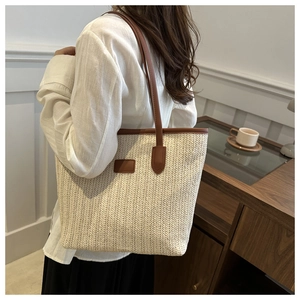 Detail of hand-woven straw tote with brown leather trim and handles for summer