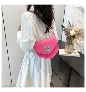 Mini sac rose fuchsia avec boucle en strass porté par un mannequin dans un décor intérieur