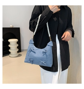 Close-up of denim tote bag featuring white pearl handle and elegant blue bows detail