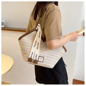 Detail of straw tote bag featuring contrast leather trim and chic ribbon decoration