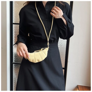 Detailed view of a mini croissant-shaped crossbody bag in cream with pleated texture