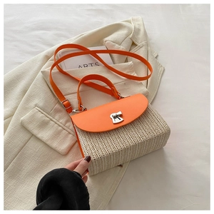 Detail of woven texture and orange leather flap with silver metal twist lock closure