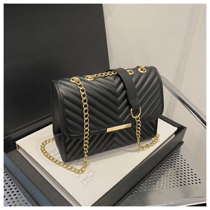 Detailed macro view of V-quilted faux leather texture and gold metal chain of the handbag