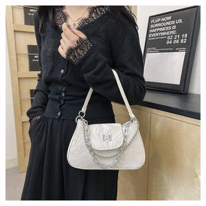 Détail de boucle papillon argentée et chaîne métallique sur sac bandoulière blanc marbré