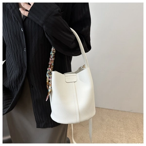 Detail der weißen Eimer-Tasche aus Lychee-Leder mit einem bunten Seidentuch am Griff