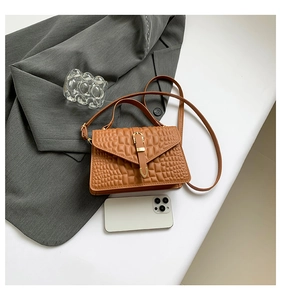 Detail of brown crocodile pattern handbag with vintage gold buckle and smooth PU leather