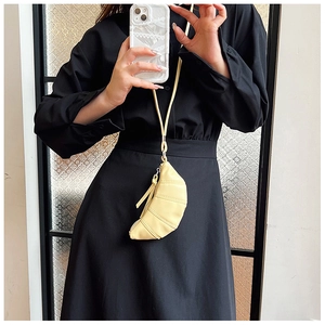 Close-up of a mini croissant-shaped neck bag in soft yellow PU leather with shoulder strap