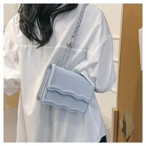 Detail of light blue crossbody bag with wavy stitching and silver chain strap