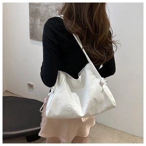 Dettaglio borsa tote bianca in morbida pelle con scritte in rilievo e design a nuvola