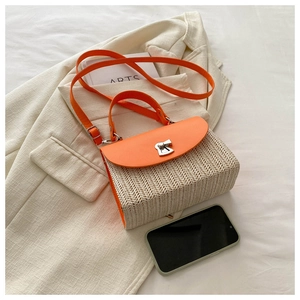 Detail of woven straw handbag with bright orange leather flap and metal turn-lock