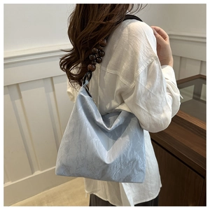 Detail of light blue pleated shoulder bag featuring unique dark brown wooden bead straps