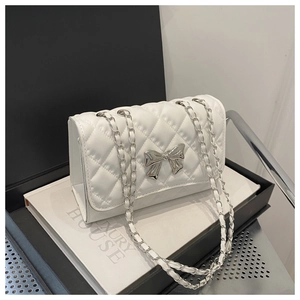 Detailed view of white quilted crossbody bag featuring silver bow clasp and chain strap