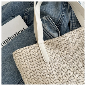 Detail of woven straw tote bag texture with creamy leather strap on blue denim