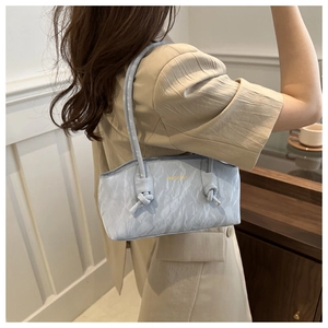 Détail du sac bandoulière bleu clair plissé avec bandoulière à nœud sur un mannequin