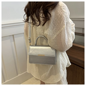 Detail of silver metallic handbag with minimalist gold buckle and sleek shoulder strap