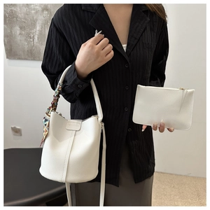 Close-up of white bucket bag with pebble leather texture and colorful silk scarf detail