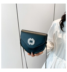 Gros plan d'un sac à bandoulière en cuir noir avec boucle ornée de strass brillants