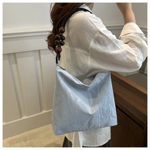 Detail view of light blue pleated velvet shoulder bag with dark wooden bead strap