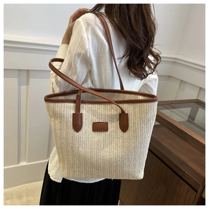 Detail of a cream woven tote bag featuring a V-shaped texture and brown leather trim