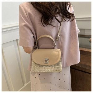 Detail of a chic straw patchwork crossbody bag with a metal lock and adjustable strap