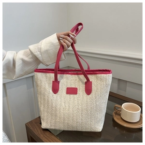 Detail of a beige straw tote bag featuring vibrant fuchsia faux leather straps and trim