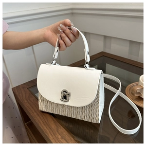 Detailed shot of textured straw and white leather patchwork handbag with silver clasp