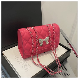 Close-up of rose red quilted chain bag with silver bow buckle and luxury box