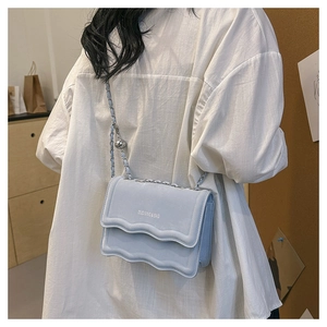 Detail of light blue chain bag with wave pleats and silver metal ball decorative strap