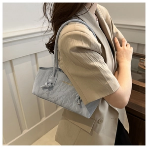 Détail du sac à bandoulière plissé bleu clair avec poignée nouée et logo doré chic