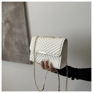 Close-up of white chevron quilted faux leather shoulder bag with gold chain and metal trim