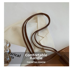 Detail of brown leather tote handle featuring elegant white contrast stitching craftsmanship