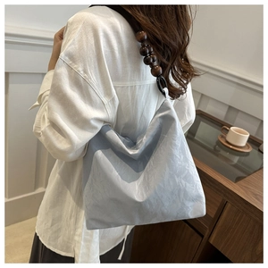 Detail of light blue pleated shoulder bag with large brown wooden bead strap design