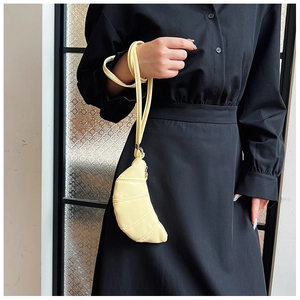 Close-up of bright yellow croissant-shaped mini bag with textured matte leather finish