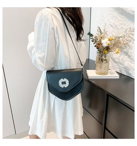 Détail d'un sac bandoulière en cuir noir avec une boucle ronde étincelante en strass