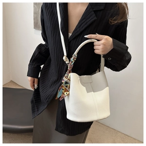 Detail of white lychee leather bucket bag with silk scarf and FASHION embossed clasp