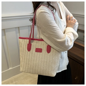 Detail of hand-woven straw tote with vibrant magenta leather handles and trim
