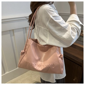 Dettaglio della borsa tote rosa in ecopelle con scritta WGONGZHU e cinturini laterali annodati