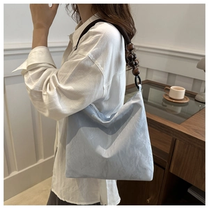 Detail of wooden beaded strap and textured silk fabric on blue single shoulder bag
